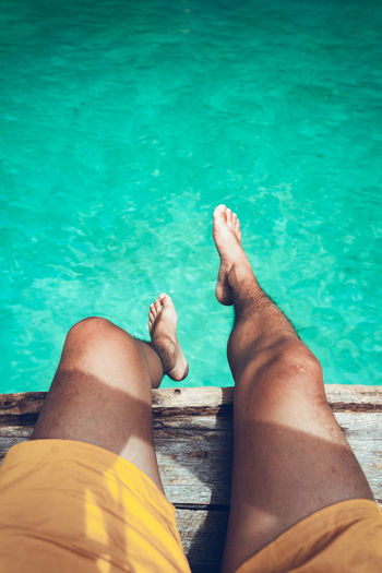 Low section of man relaxing on boat over sea