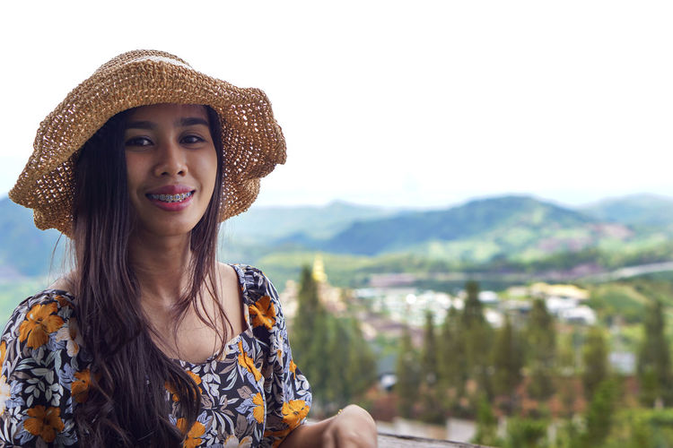 Portrait of smiling young woman against mountains