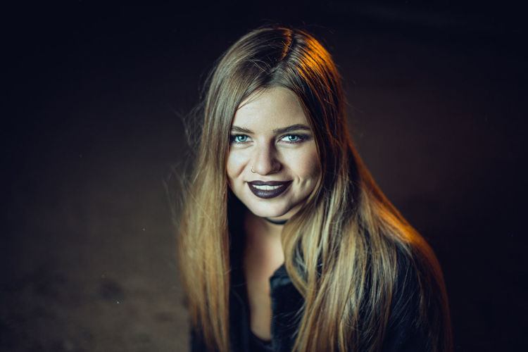 Portrait of young woman with black lipstick having long blond hair