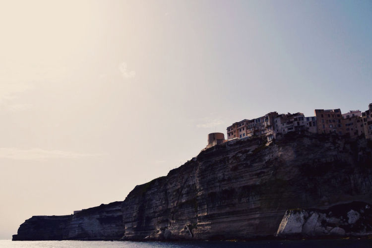 Low angle view of city on beach cliff against sky