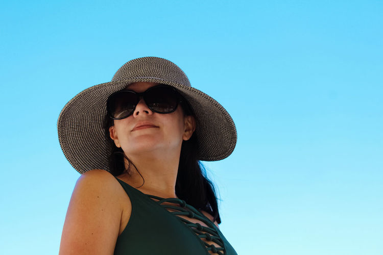 Young woman wearing hat against clear blue sky