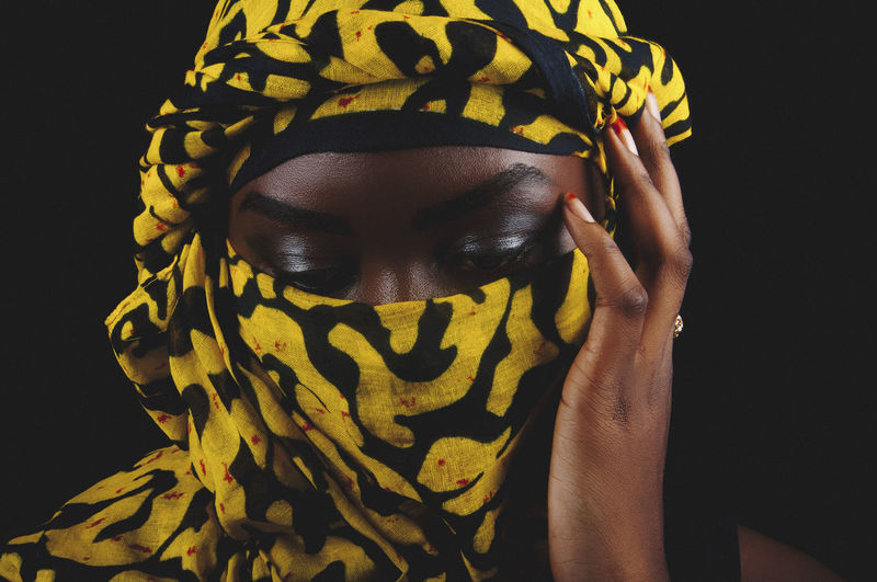 Close-up of woman wearing scarf against black background