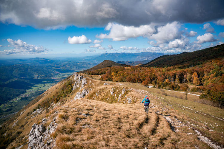 Woman mountain biking on footpath near ridge on mount nanos above vipava, slovenia.