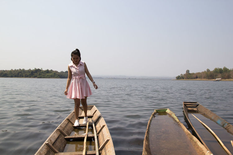 Young woman standing on boat by sea against clear sky