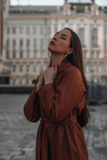 Outdoor autumn portrait of young elegant fashionable woman wearing trendy brown leather coat