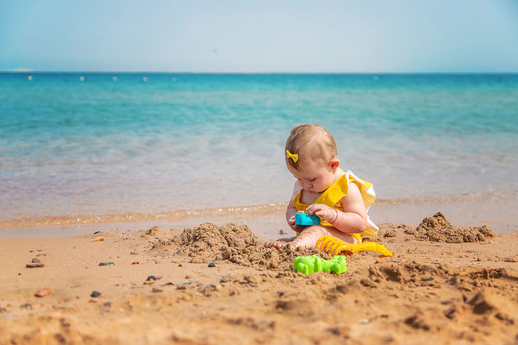 Baby girl playing with toy at beach