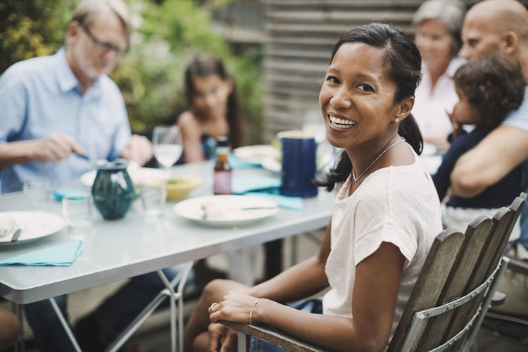Portrait of happy woman sitting with family at outdoor dining table