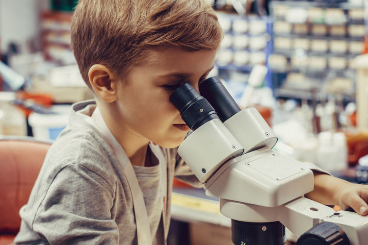 Small kid using microscope in engineering lab.