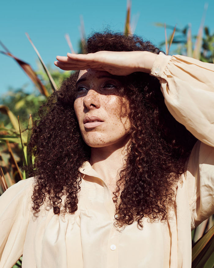 Close-up of woman shielding eyes against plants
