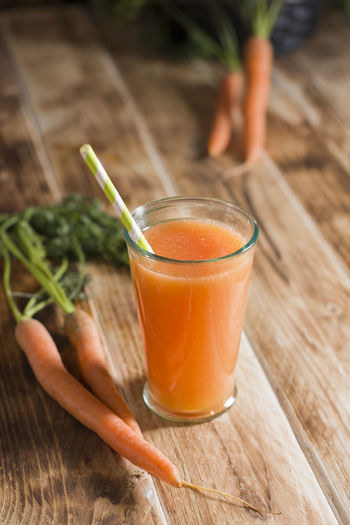 Freshly squeezed carrot juice, and raw carrots, vegetarian vegetable vitamin drink, rustic stillife