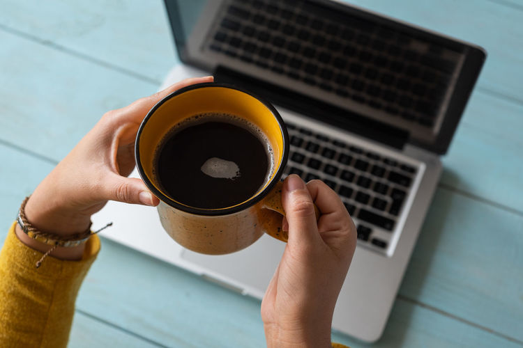 High angle view of hand holding coffee cup