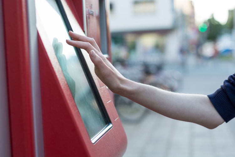 Cropped hand using ticket machine in city