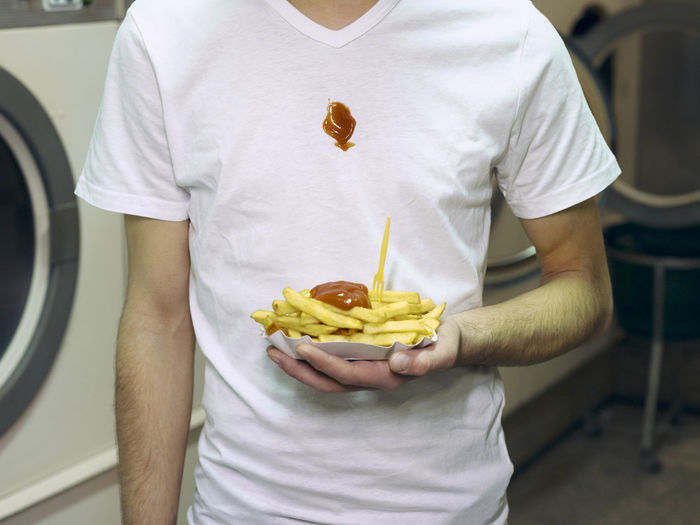 Midsection of man holding french fries in paper plate