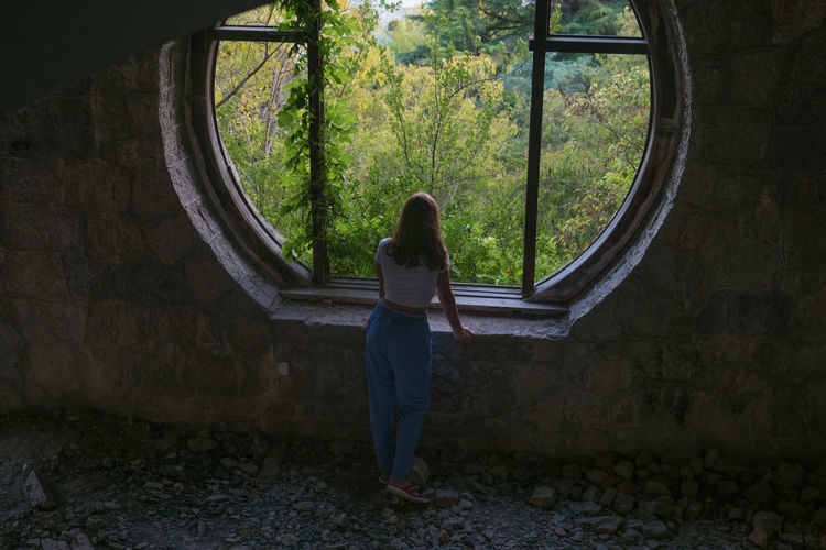 Teen girl standing by the window in an abandoned building