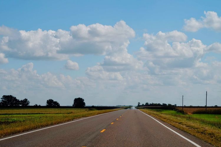 Road amidst field against sky