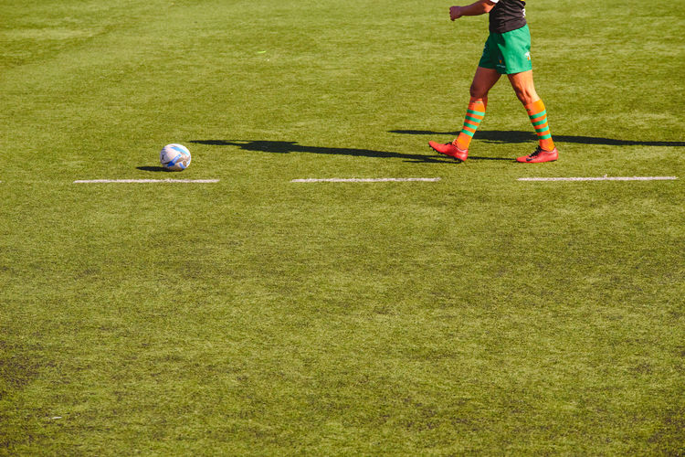 Low section of man playing soccer on grass
