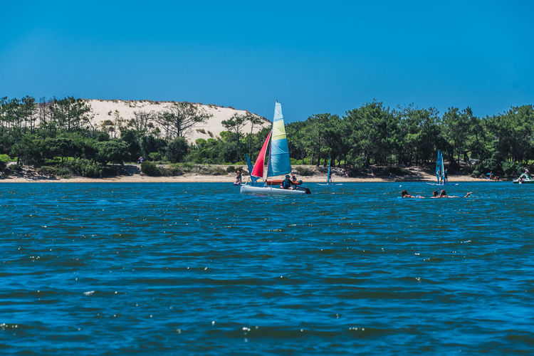 Sailboat in sea against clear blue sky
