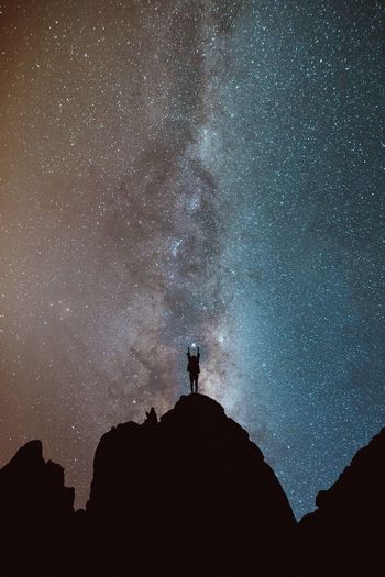 LOW ANGLE VIEW OF SILHOUETTE PERSON STANDING ON ROCK AGAINST SKY