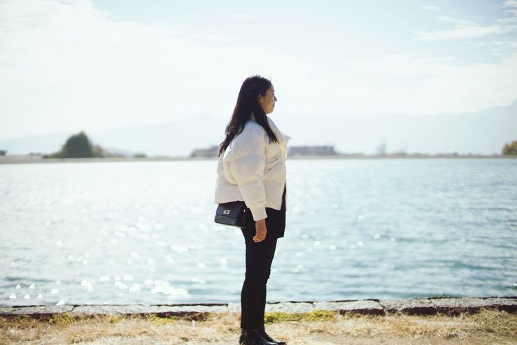 Side view of woman standing against sea 