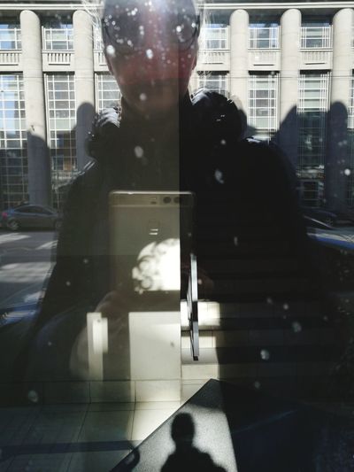 Reflection of woman photographing in city