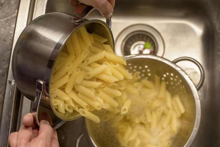 Midsection of person preparing pasta in kitchen