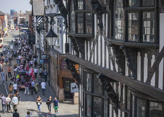 People walking on street amidst buildings in city of chester, england