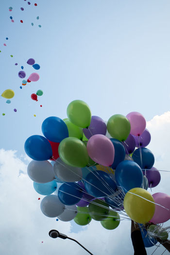 Low angle view of multi colored balloons against sky