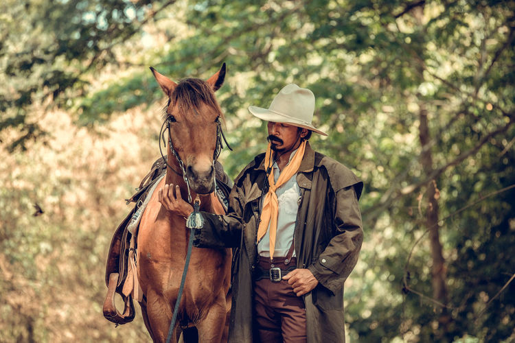 Cowboy with horse standing in forest