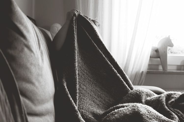 Person covered in blanket sitting on sofa at home