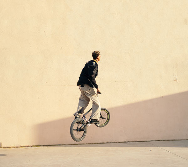Full length of man riding bicycle on wall