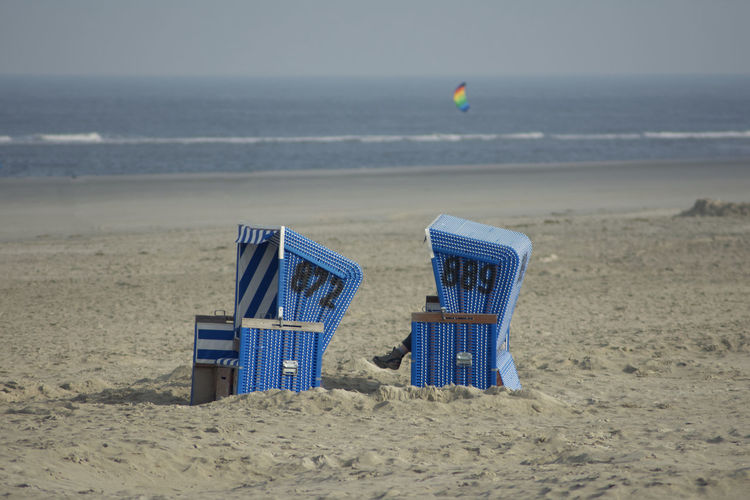 Hooded chairs on beach against sea