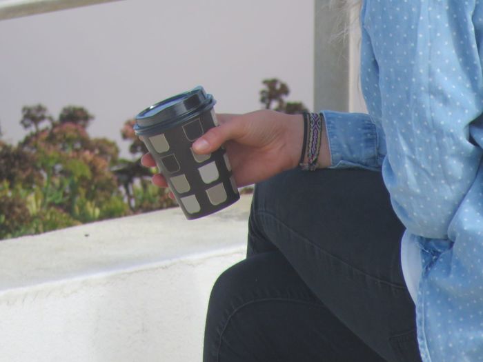 Midsection of woman photographing with coffee cup