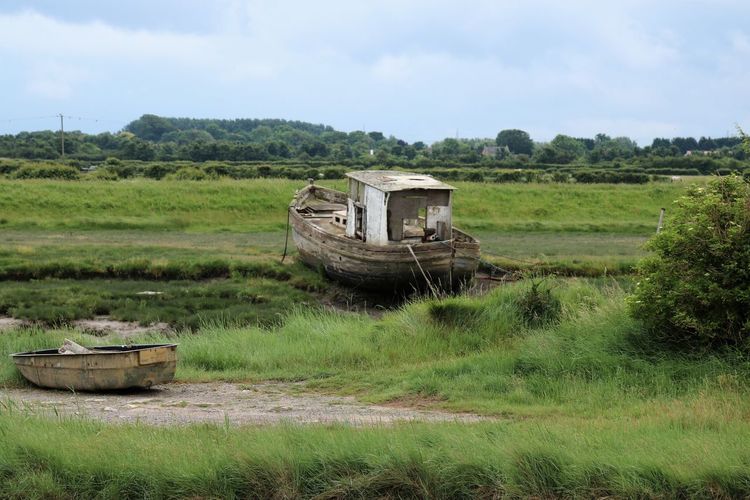 View of abandoned boats on grassy field 