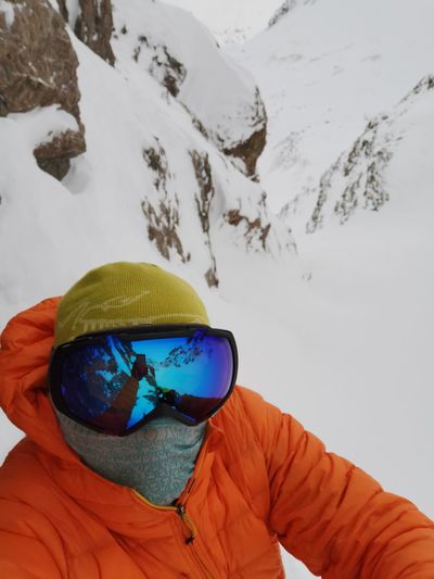 Portrait of man wearing sunglasses standing on snow covered mountain
