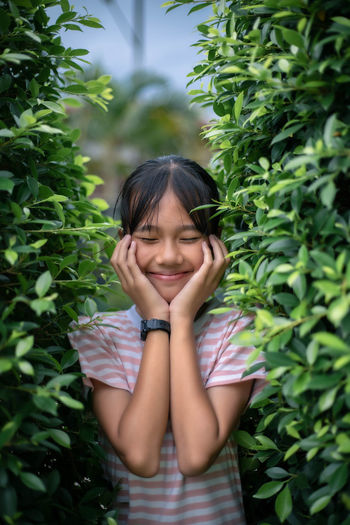 Portrait of a smiling girl standing against plants