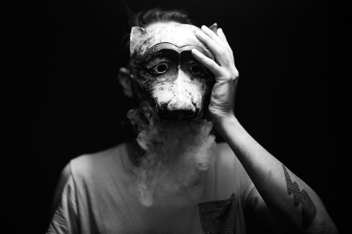 Man wearing animal mask while standing against black background