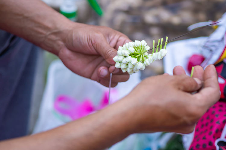 Close-up of hands man holds the needle and making jasmine garland.