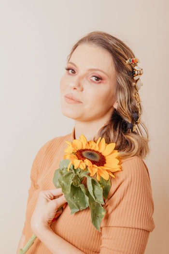 Portrait of young woman with bouquet against white background