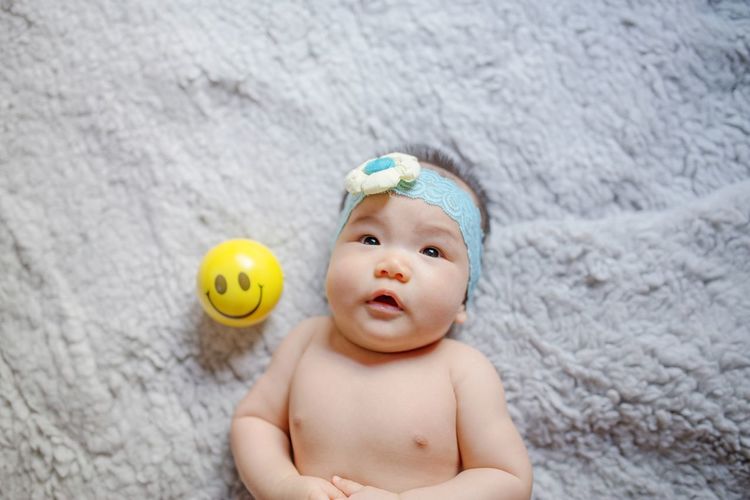 High angle view of cute baby girl by ball on carpet
