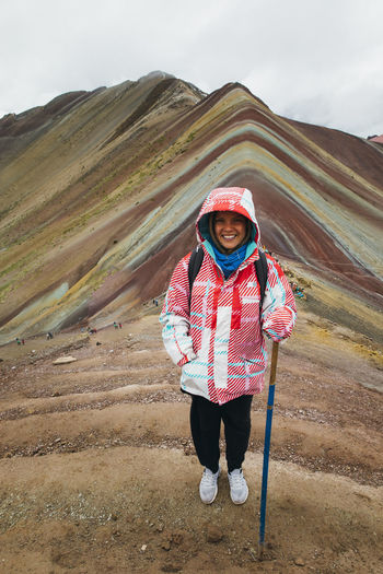 A young woman is standing on the famous rainbow mountain in peru