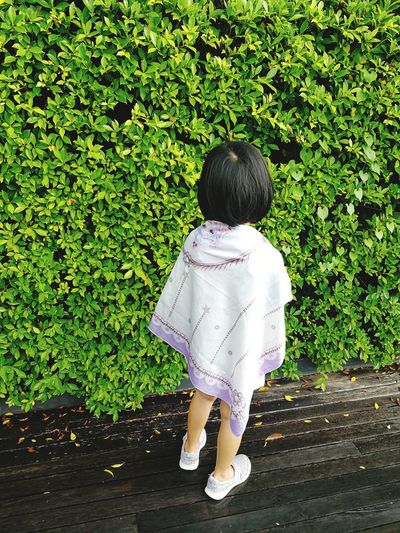 Rear view of girl standing against plants
