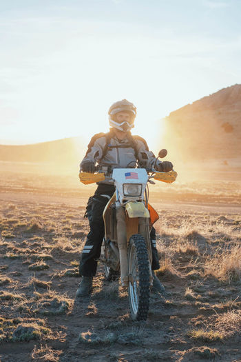 Man on motorcycle in desert during sunset