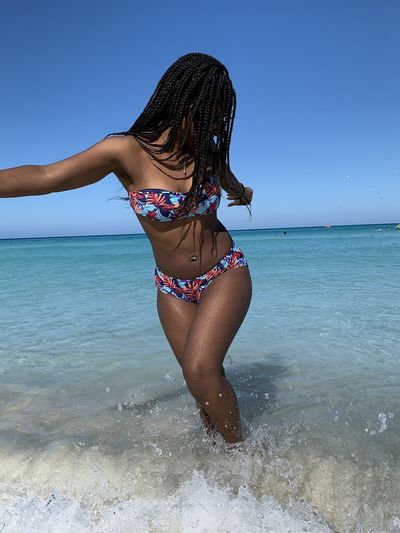 Full length of woman in bikini at beach against sky