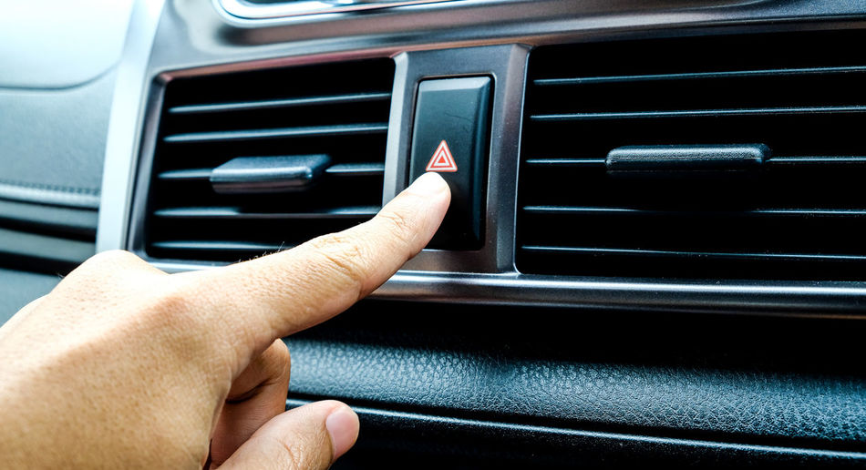 Close-up of hand pressing push button in car