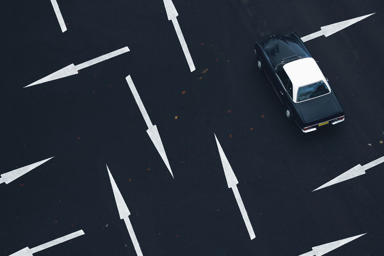 Abstract city life. high angel view of a classic car against a multi directional road arrows.