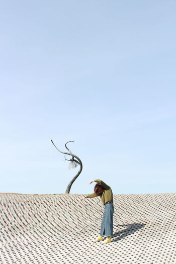 Side view of man on roof against sky