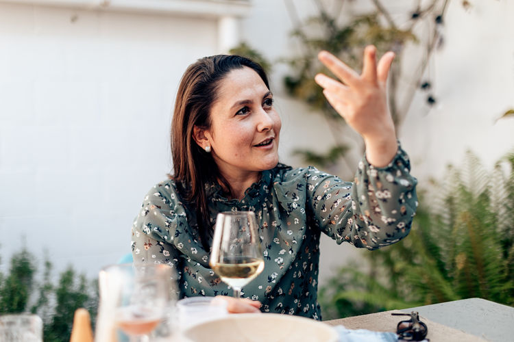 Woman sitting speaks cheerfully raising her arm and gesturing with her hand to reinforce her speech