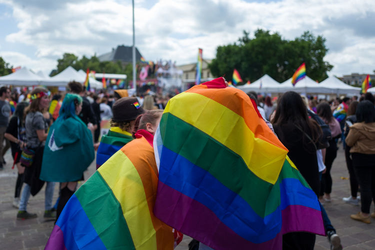 People covered with rainbow flags on street during gay pride parade