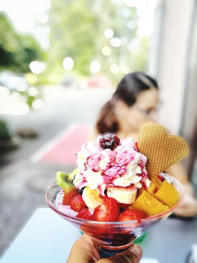 Cropped image of person holding ice cream sundae outdoors