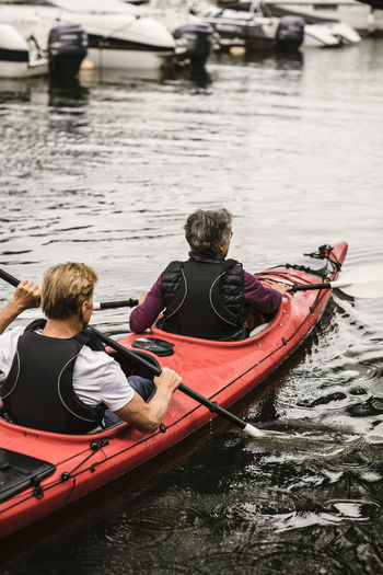 Rear view of senior woman and man kayaking in sea during training course